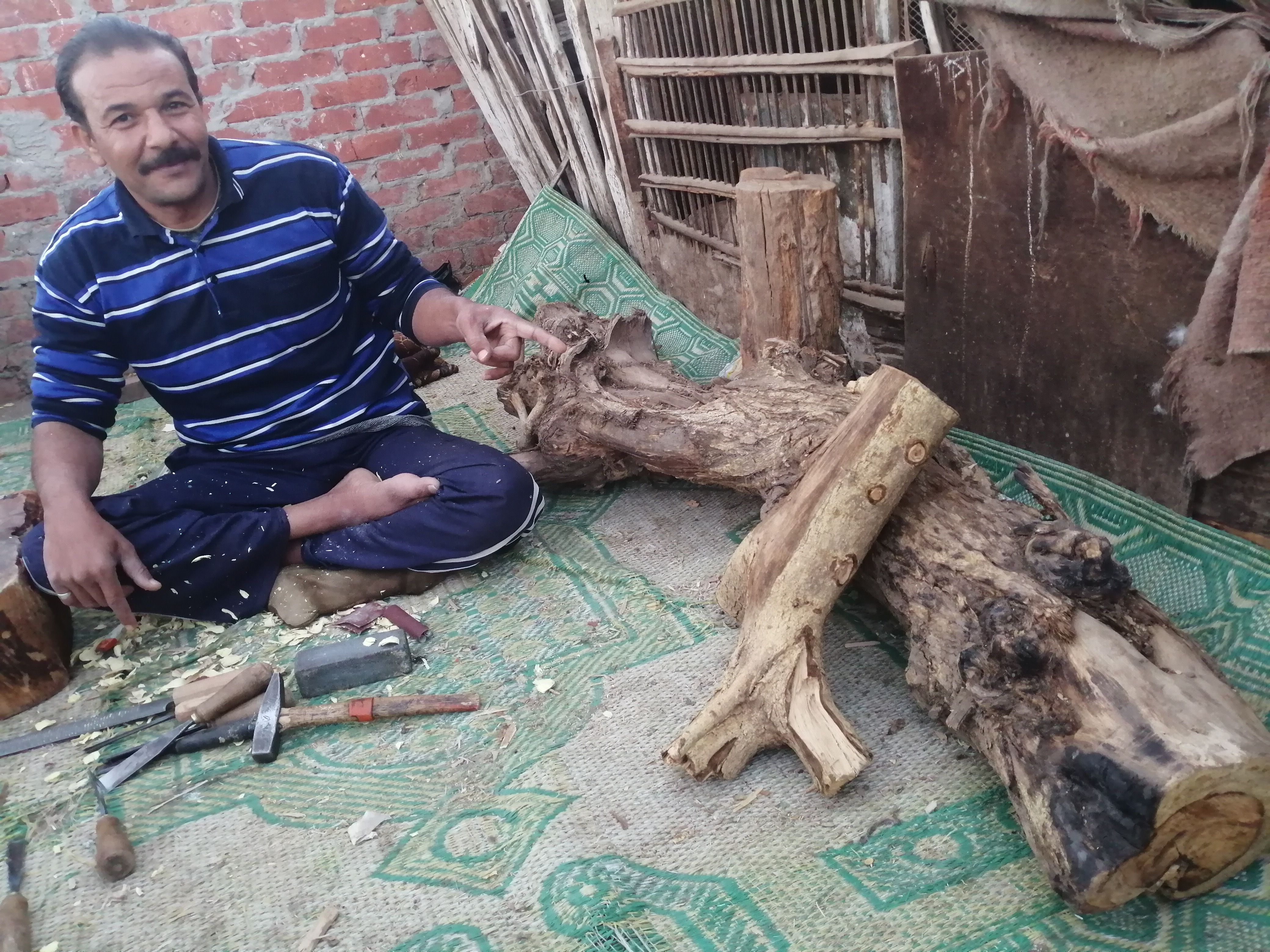 "مفيش مستحيل".. أحمد يتحدى إعاقته بنحت تماثيل خشب على سطح منزله ببنى سويف.. ويؤكد: أصبت...