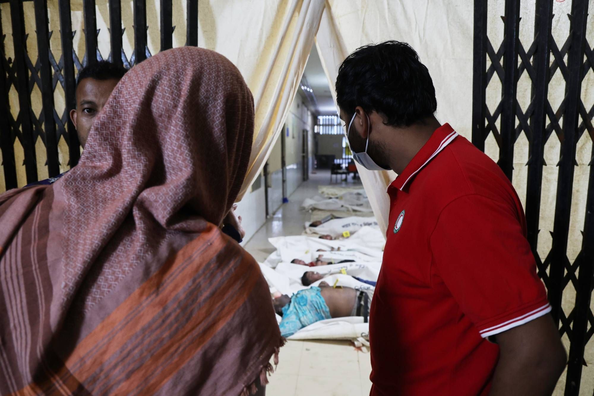 يحاول الناس التعرف على أقاربهم المتوفين في مستشفى راجباري الحكومي في اليوم التالي لسقوط حافلة ركاب في نهر بادما (أ.ب)